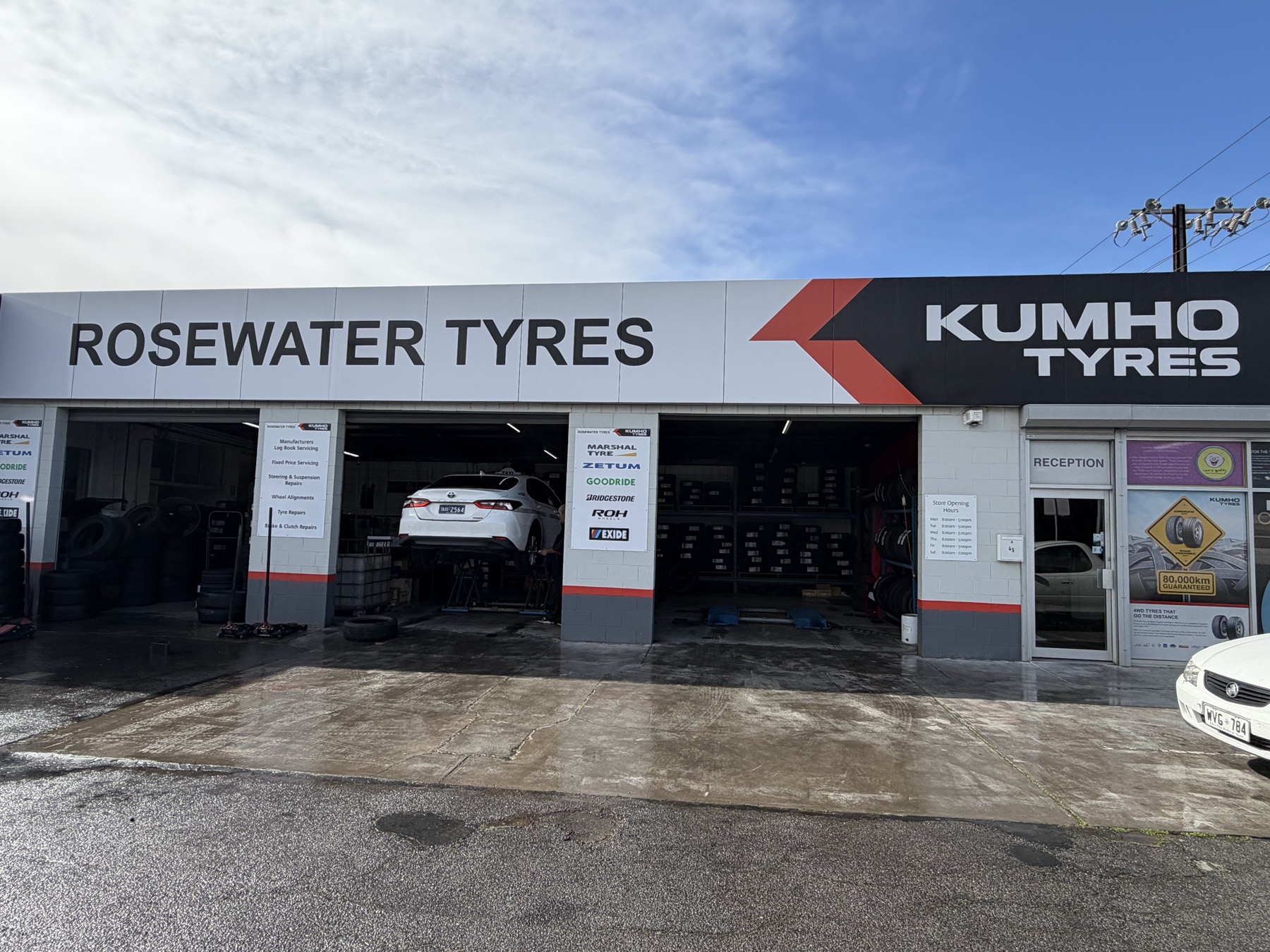 The Rosewater Tyres workshop in Adelaide, three service bays open with a car on the hoist